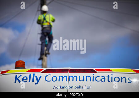 Telecome entrepreneurs Ingénieur de Kelly Communications escalade un poteau téléphonique pour fixer une ligne téléphonique sous-traitant travaillant pour BT Openreach en ma Banque D'Images