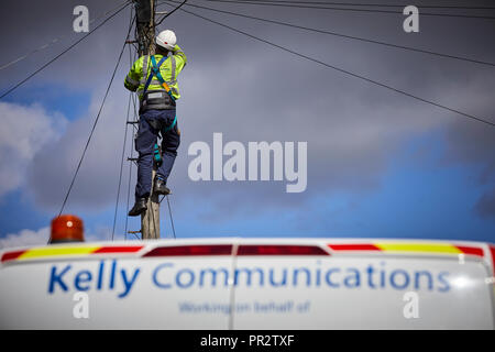 Telecome entrepreneurs Ingénieur de Kelly Communications escalade un poteau téléphonique pour fixer une ligne téléphonique sous-traitant travaillant pour BT Openreach en ma Banque D'Images