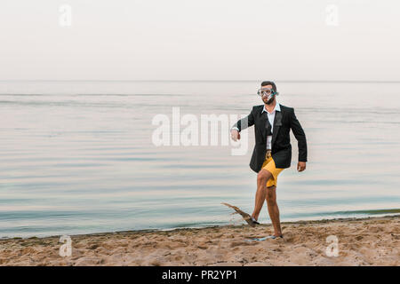 L'homme en noir veste et pantalon avec pied natation masque et des palmes sur mer Banque D'Images