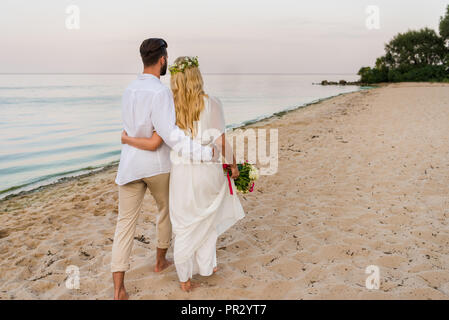 Vue arrière du couple hugging and walking on beach Banque D'Images