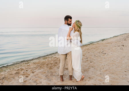 Vue arrière du couple hugging, marcher et aller de l'embrasser sur la plage Banque D'Images