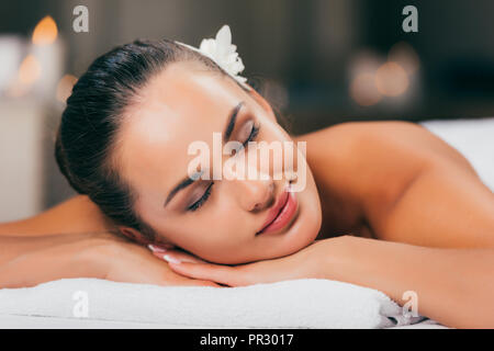 Jeune femme avec des fleurs dans les cheveux de dormir à spa salon Banque D'Images