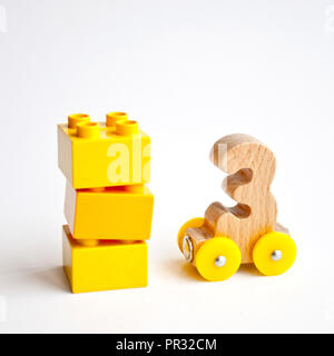 Les numéros en bois 0, 1, 2, 3,4,5 lettres alphabet voitures de train avec roues jaune sur fond blanc. L'éducation de la petite enfance, apprendre à compter, presch Banque D'Images