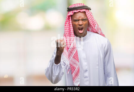 Jeune arabe african man wearing keffieh traditionnel sur fond isolé en colère et frustrés et poing de fou furieux tout en criant avec un Banque D'Images