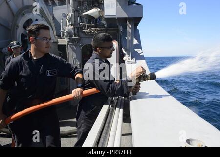 MUTSU, le Japon (26 juillet 2017) - Senior Airman Dhruv Gopinath exploite un tuyau d'incendie sur l'USS Pioneer comme pompier-électricien, Nicholas Burns assiste pendant 2JA 2017 Exercice de lutte contre les mines (2JA-17 MCMEX). 2JA Lutte contre l'exercice est un exercice bilatéral annuel qui a eu lieu entre la Marine américaine et à renforcer l'interopérabilité et JMSDF compétences augmenter dans les opérations de lutte contre les mines. Banque D'Images