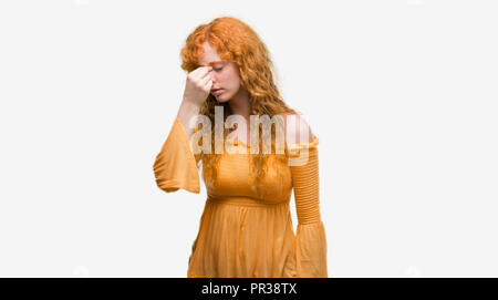 Jeune femme rousse fatigué se frottant le nez et les yeux sentant la fatigue et les céphalées. Le stress et la frustration concept. Banque D'Images