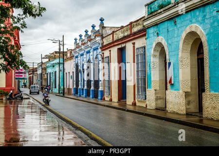 Ancienne colonie espagnole coloré décoré maisons individuelles de l'autre côté de la rue humide après la pluie dans le centre de Camaguey, Cuba Banque D'Images