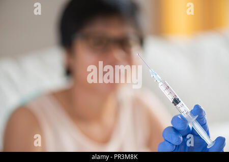 Médecin pour faire une injection de vaccin pour une fille. Petite fille avec sa mère sur l'arrière-plan. Banque D'Images