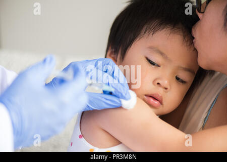 Médecin pour faire une injection de vaccin pour une fille. Petite fille pleurer avec sa mère sur l'arrière-plan. Banque D'Images