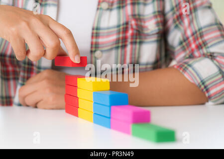 Concept de la fondation du succès. Les femmes part mettre les blocs en bois coloré en forme d'un escalier Banque D'Images