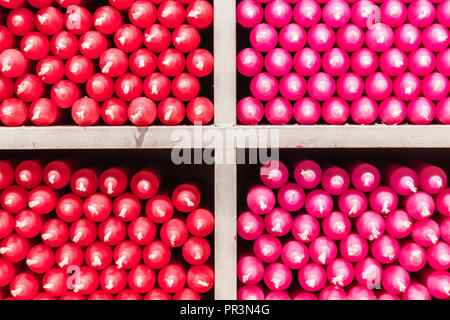 Couleur multicolore rouge et rose stick paraffine des bougies disposées sur des étagères dans un magasin Banque D'Images