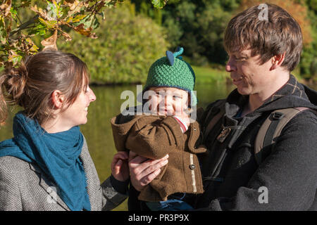 Un couple et leur bébé fils : sourires heureux à Sheffield Park, East Sussex, Angleterre, Royaume-Uni. MODÈLE LIBÉRÉ Banque D'Images