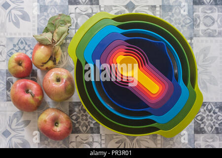 Fraîchement cueilli, pommes biologiques sur une table avec des bols et des tasses à mesurer, prêts à être cuisinés. Banque D'Images