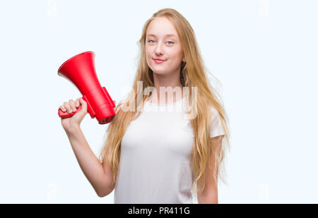 Adolescent Blond woman holding megaphone avec un visage heureux et souriant debout avec un sourire confiant montrant les dents Banque D'Images