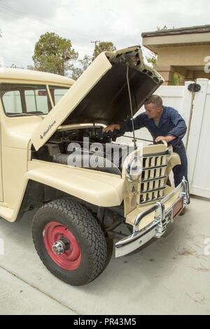 Le Lieutenant-Colonel Timothy Silkowski, directeur de la Division de l'appui de la flotte, ajuste le collecteur d'admission sur le carburateur de son 1950 Jeep Willys Station Wagon à bord, Marine Corps Base Barstow, Californie, le 25 juillet. Il a trouvé le véhicule abandonné et enterré jusqu'à la roue des puits dans le sable, et a travaillé avec diligence à la restaurer dans ses temps libres. Banque D'Images