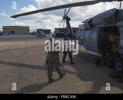 La NORFOLK (sept. 11, 2018) en prévision de l'arrivée de l'ouragan Florence, de marins de la mer de l'escadron de combat d'hélicoptère (HSC) 28 Chargement d'un MH-60S Sea Hawk avec des approvisionnements, qui se préparent à évacuer Norfolk Naval Station d'assurer la sécurité du personnel et éviter les dommages à l'actif de la Marine comme d'une mesure proactive. Plus de 100 routes de Hampton basé aéronefs affectés à la Marine, commandant de l'Atlantique de la Force aérienne ont quitté la région à la suite de l'orage. Les avions sont détournés de leurs bases en six autres États qui ne sont pas menacées par l'ouragan. Commandant, Commandement de la flotte américaine ord Banque D'Images