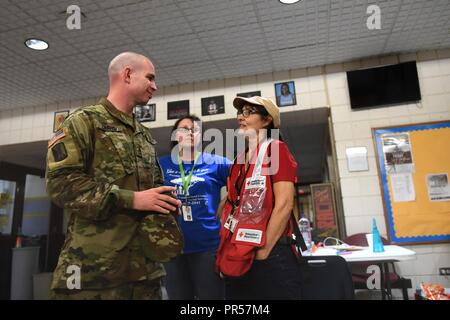 Le sergent de l'armée américaine. Gary Chavis de la Garde nationale de Caroline du Nord des entretiens avec des membres de l'American Red Cross refuge après la livraison des lits bébés et des couvertures à la suite de l'ouragan Florence en Fayetteville, NC, le 16 septembre 2018. Gardes nationaux transporté plus de 300 800 lits et des couvertures pour huit différents refuges au Fayetteville. L'ouragan Florence est l'une des plus grandes tempêtes pour frapper les deux Caroline en années et a suscité une réaction massive de services d'urgence. Banque D'Images