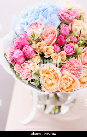 Beau bouquet de fleurs de printemps. arrangement avec différentes couleurs de vase en verre rose sur table. Cette chambre lumineuse, mur blanc. Banque D'Images