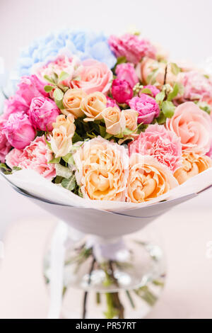 Beau bouquet de fleurs de printemps. arrangement avec différentes couleurs de vase en verre rose sur table. Cette chambre lumineuse, mur blanc. Banque D'Images