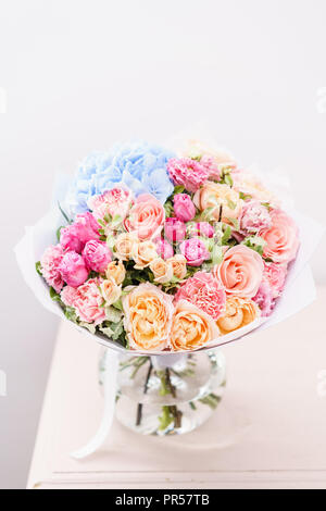 Beau bouquet de fleurs de printemps. arrangement avec différentes couleurs de vase en verre rose sur table. Cette chambre lumineuse, mur blanc. Banque D'Images