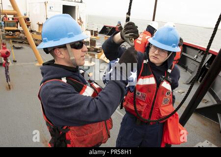 Mer de Béring - U.S. Coast Guard Charlie Seaman Cabe (à droite) et Frank Seaman Lenihan clip d'un drapeau sur une corde sur l'arc de les garde-côte Healy (WAGB-20) Dimanche, Septembre 16, 2018, dans la mer de Béring. L'équipage du navire ancré près de Nome, en Alaska, afin de recevoir de l'équipement scientifique qui seront déployées dans l'Arctique. Le drapeau est relevé à chaque fois que le navire est amarré à un quai ou au mouillage. La Healy est l'un des deux brise-glace en service et est le seul navire militaire dédié à la conduite de la recherche sur les glaces de l'Arctique. La Garde côtière américaine Banque D'Images