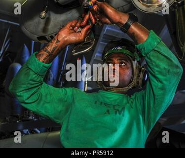 Mer des Philippines (Septembre 1994). 15, 2018) l'Aviation aviateur Joel-Marc Lobban, mécanicien de Kingsland, Jamaïque, s'occupe de l'entretien d'un MH-60S Sea Hawk affectés à l'Escadron d'hélicoptères de combat de la mer (HSC) 12 dans la zone de déploiement de la marine de l'avant-porte-avions USS Ronald Reagan (CVN 76) en vue de l'exercice Valiant Shield en 2018. Valiant Shield est une biennale, seulement un exercice d'entraînement sur le terrain (FTX) avec un accent sur l'intégration de la formation conjointe de couleur bleu-eau environnement parmi les forces américaines. Cette formation permet la maîtrise mondiale dans le maintien de forces conjointes par la détection Banque D'Images