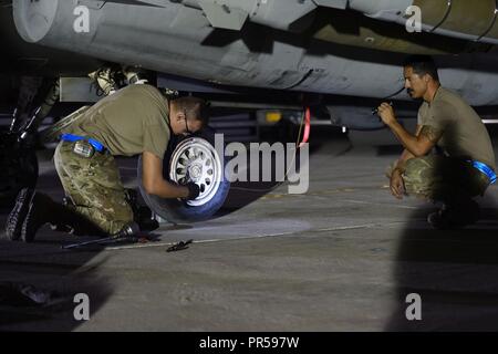 Juanluis Senior Airman Cota, 157e Escadron de chasse de l'expéditionnaire, chef de l'équipe détient une lumière flash alors que l'Aviateur Senior Connor Stuart, 157e chef d'équipe de l'EFS, les changements d'un pneu sur un F-16 Fighting Falcon après l'atterrissage dans un endroit inconnu en Asie du Sud-Ouest, le 13 septembre 2018. Le F-16 Fighting Falcon est un appareil compact, multi-rôle d'avions de chasse. Il est très manoeuvrable et a fait ses preuves dans les combats air-air et air-surface attaque. Il peut localiser des cibles dans toutes les conditions météorologiques et de détecter les aéronefs volant à basse altitude dans l'encombrement du radar. Banque D'Images