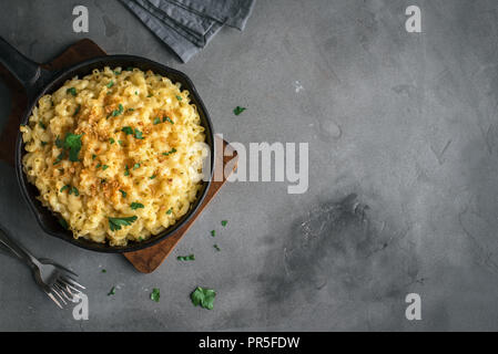 Mac et fromage, american style macaroni pâtes avec sauce au fromage et chapelure croquante topping sur table béton, copie espace Vue de dessus Banque D'Images