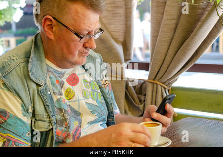 Portrait of handsome man, qui utilise son smartphone tout en étant assis dans le café. Close-up. Banque D'Images