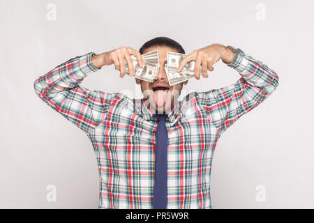 Rendez fou avec succès ! Riche beau barbu en chemise à carreaux colorés avec cravate bleue et permanent couvrant les yeux avec de l'argent avec ventilateur ou langue maternelle Banque D'Images