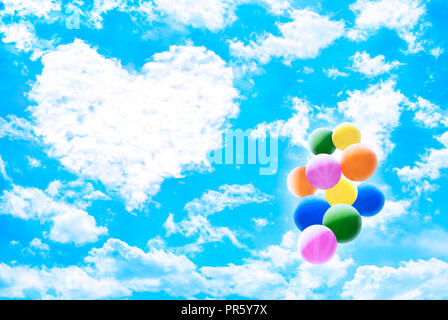 Les nuages blancs sur ciel bleu formant des "coeur" avec des tas de ballons colorés. Concept de la Saint-Valentin. Banque D'Images