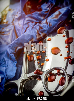 Bleu Gants et ciseaux tachés de sang sur un plateau dans une salle d'opération, conceptual image Banque D'Images