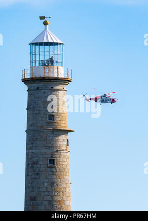 HM Coastguard hélicoptère volant près de l'ancien phare de lumière pendant une opération de sauvetage sur l'île de Lundy au large de la côte du Devon UK Banque D'Images