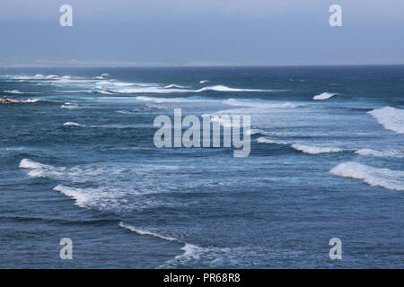 Vagues de l'océan Pacifique en roulant alors que les surfeurs à palette à Paia Hookipa Beach, Maui, États-Unis sur une journée brumeuse Banque D'Images