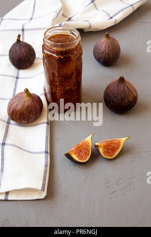 Confiture de figues dans un bocal en verre et figues fraîches sur fond gris, vue de côté. Libre. Banque D'Images