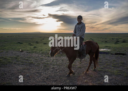 Un homme vu son cheval équitation pour ramener son bétail près de la ville de Saikhan Ovoo en Dundgovi, Province sud de la Mongolie. Banque D'Images