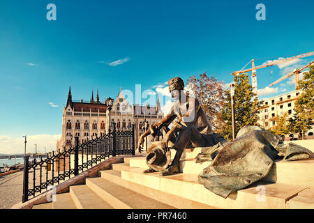 Statue du célèbre poète hongrois Jozsef Atilla à Budapest avec la Chambre du Parlement dans l'arrière-plan. Banque D'Images