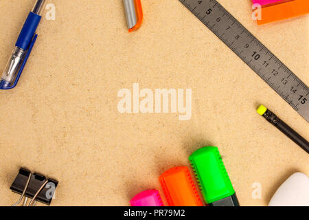 Papeterie (stylos, crayons, règle, gomme, collier et autocollants) se coucher sur le sable. Vue d'en haut Banque D'Images