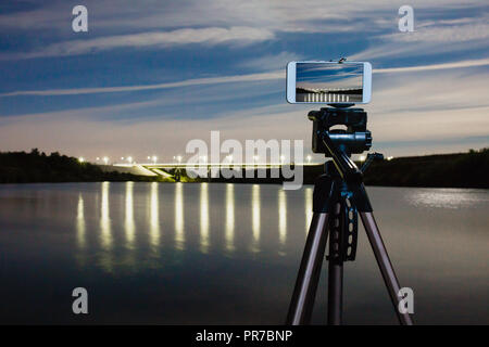 En utilisant comme smartphone appareil photo professionnel sur trépied pour la capture de nuit paysage avec beaucoup de lumière reflétée sur surface de l'eau Banque D'Images