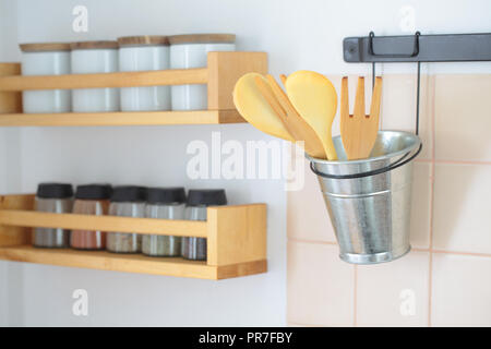 Spatules en bois sur un support et d'étagères avec des épices sur un mur de cuisine Banque D'Images
