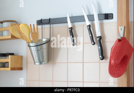 Spatules en bois sur un support et des couteaux de cuisine sur un support magnétique Banque D'Images