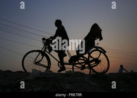 Dhaka, Bangladesh. Sep 30, 2018. Un rickshaw puller silhouette contre le soleil comme sa recherche d'un frontalier dans les exilés d'Gabtoli, un quartier de Dhaka. Credit : MD Mehedi Hasan/ZUMA/Alamy Fil Live News Banque D'Images