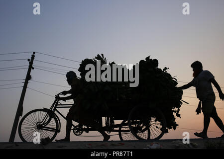 Dhaka, Bangladesh. Sep 30, 2018. Un van extracteur et un travailleur silhouette contre le soleil qu'ils livrent des chuchotements d'un fourgon dans les exilés d'Gabtoli, un quartier de Dhaka. Credit : MD Mehedi Hasan/ZUMA/Alamy Fil Live News Banque D'Images