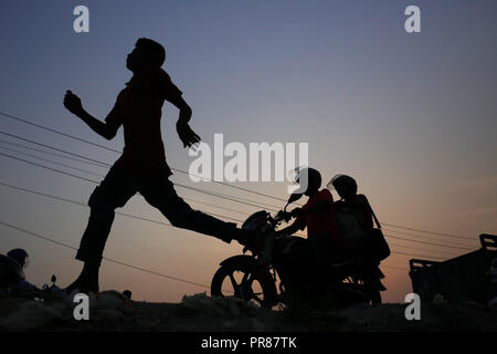 Dhaka, Bangladesh. Sep 30, 2018. Un garçon et biker silhouette contre le soleil qu'ils retournent à la maison du travail dans les exilés d'Gabtoli, un quartier de Dhaka. Credit : MD Mehedi Hasan/ZUMA/Alamy Fil Live News Banque D'Images