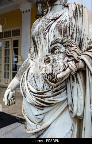 Palais Achilleion, Corfou, Grèce - 24 août 2018 : Un masque tragique dans la main d'une statue d'Melpomene, la muse de la tragédie, sur le balcon de l''Achillion Banque D'Images