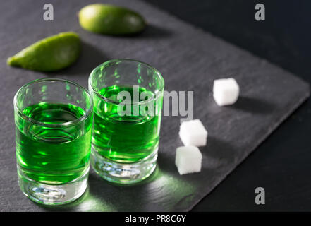 Deux verres à absinthe vert lime et le sucre sur un fond sombre Banque D'Images