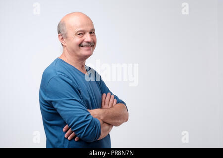 Portrait of mature homme européen avec moustache en chemise bleue ayant les bras croisés, looking at camera Banque D'Images