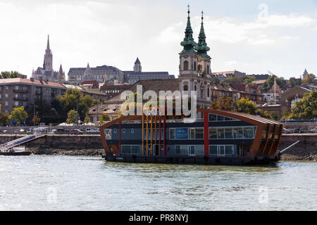 L'événement Duna bateau sur la rive Buda du Danube à Budapest, avec St Anne's Church ou lycée Église Szent Anna derrière elle et Matthias Ch Banque D'Images