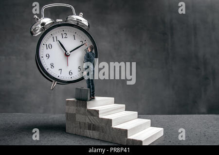 Businessman se tient sur les escaliers et tente de changer la position de l'horloge. La conception surréaliste de temps problème dans les entreprises. Banque D'Images