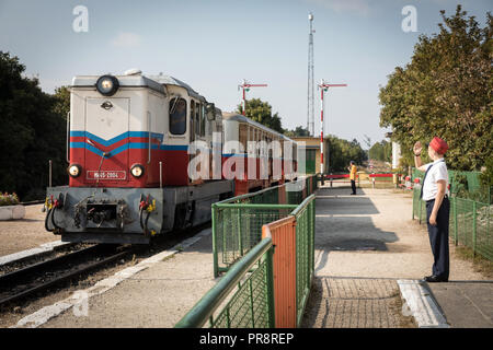 Un membre du personnel salue comme un train arrive à la station Széchenyi-hegy sur le chemin de fer pour enfants à Budapest Banque D'Images